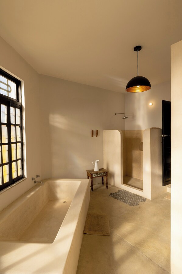 A modern bathroom with a large bathtub, a shower enclosure, and a pendant light. - Casa de Cortes (Mérida)