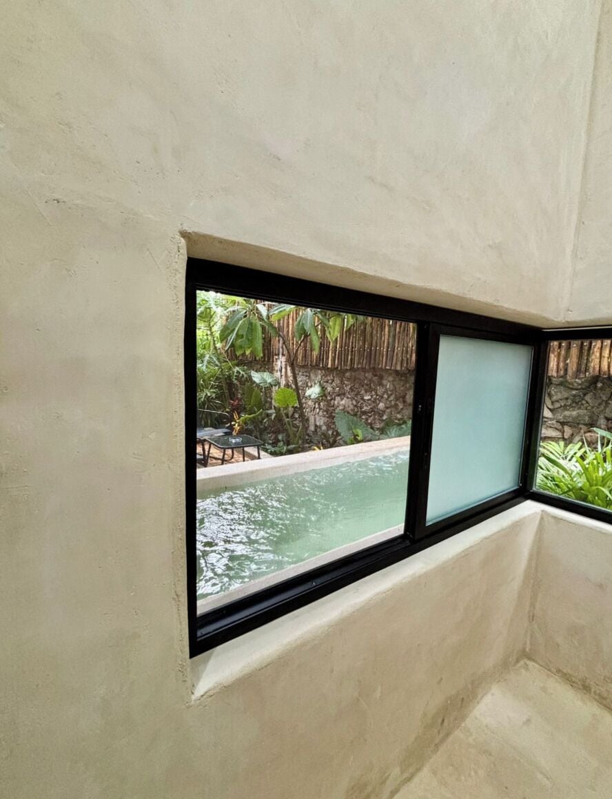 A room with a window overlooking a pool and outdoor area.