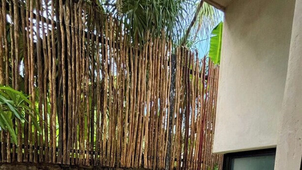 Uma área de spa com uma banheira de hidromassagem retangular, parede de bambu e parede de pedra.