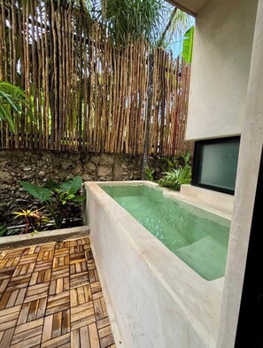 A spa area with a rectangular hot tub, bamboo wall, and a stone wall. - Casa de Cortes (Mérida)