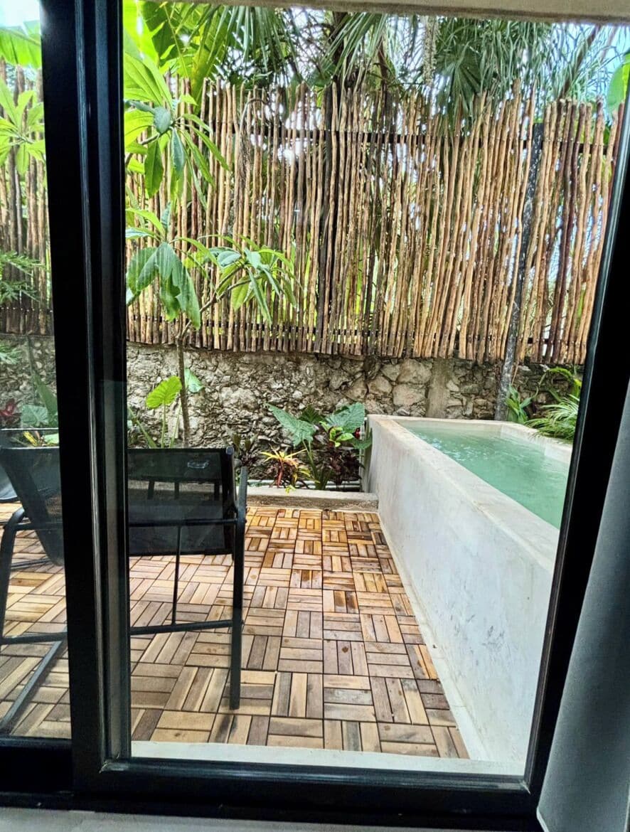 A wooden deck with a bench, a stone wall, and a bamboo fence.