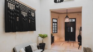 Um interior moderno com um sofá, uma planta em vaso e um painel decorativo na parede.