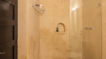 Un baño con cabina de ducha de vidrio, inodoro blanco y puerta de madera oscura.