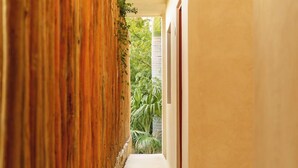 Um corredor com parede de bambu, piso ladrilhado e vista para o verde lá fora.