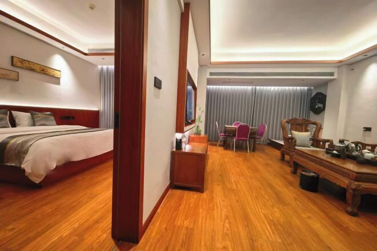 A hotel room with a bed, a desk, a chair, and a dining table.