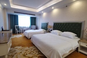 Habitación de hotel con dos camas, un escritorio, una silla y una ventana con cortinas.