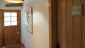 A hallway with a wooden door labeled "The Snug," a frosted glass window, and a hanging pendant light. - The Yorkshire Dales Snug - Walkers' Delight - Pet Friendly (Buckden)