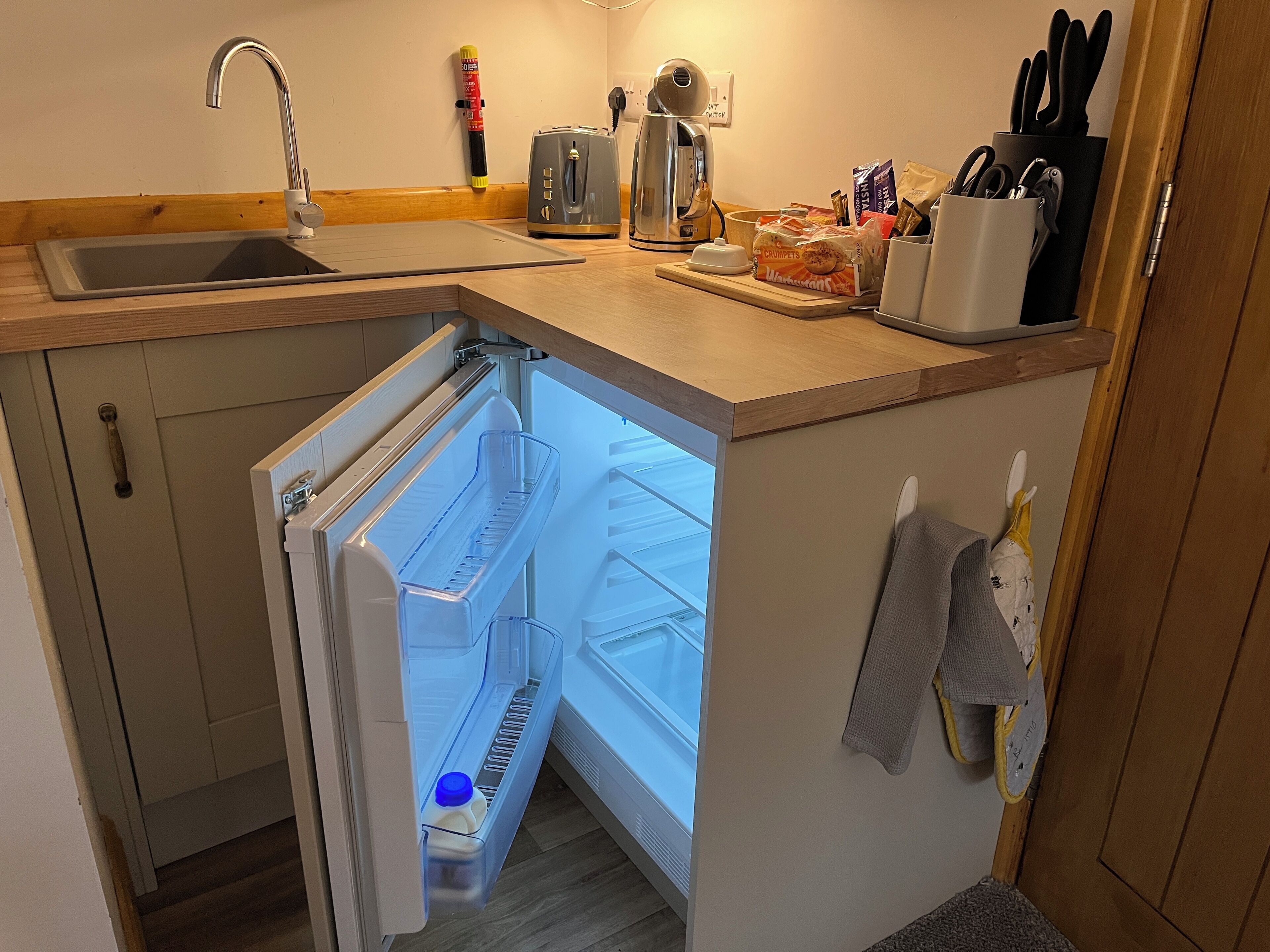 A compact kitchen with a built-in refrigerator, a sink, and a toaster.