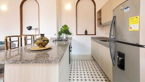 Een keuken met een granieten aanrecht, een roestvrijstalen koelkast en een betegelde vloer.