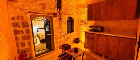 Um quarto aconchegante com parede de pedra, armários de madeira, uma mesa pequena com uma cadeira e uma cama com janela.