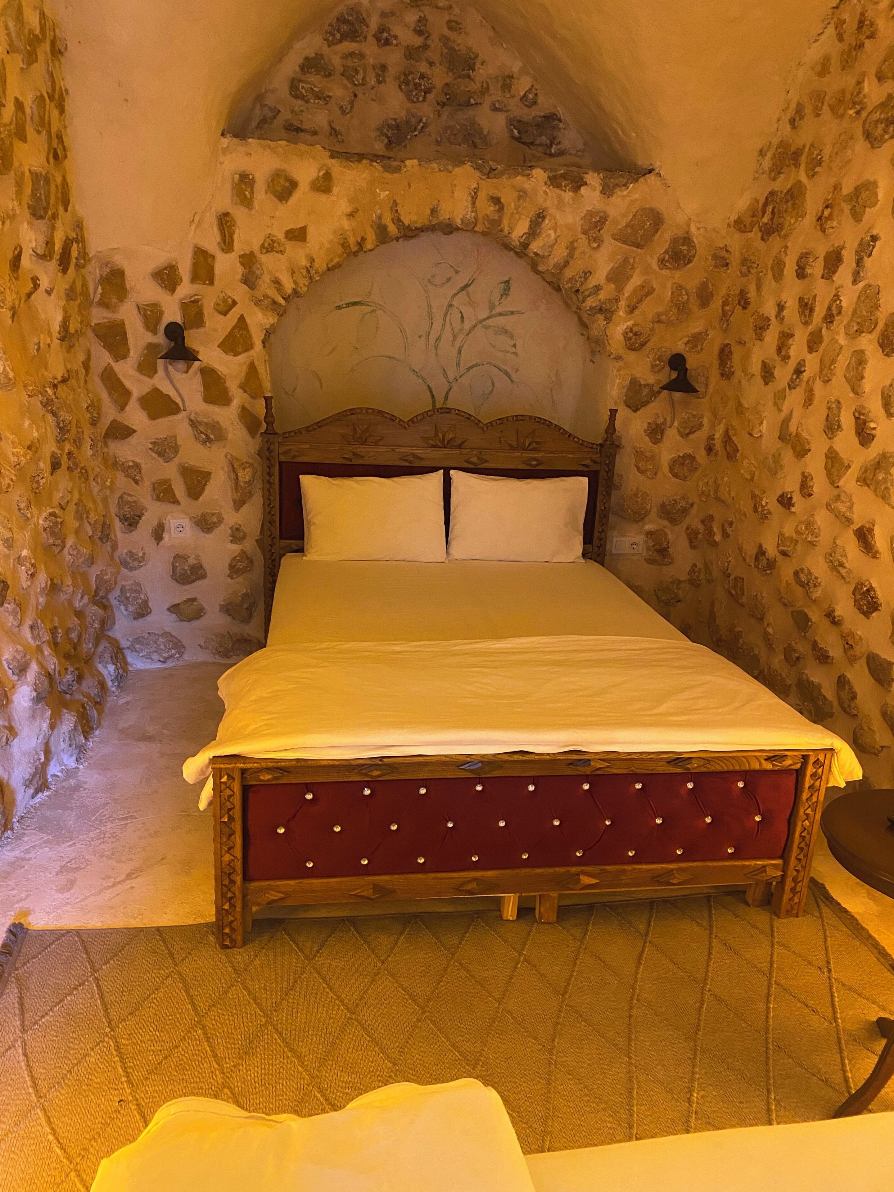 Habitación con paredes de piedra y una cama en el centro.