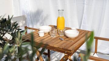 Une table en bois, dressée avec des bols blancs, des verres et une bouteille jaune, qui contient probablement une boisson.