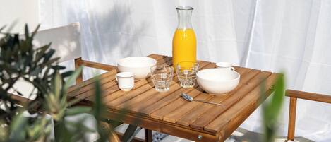 A wooden table set with white bowls, glasses, and a yellow bottle, likely containing a beverage.