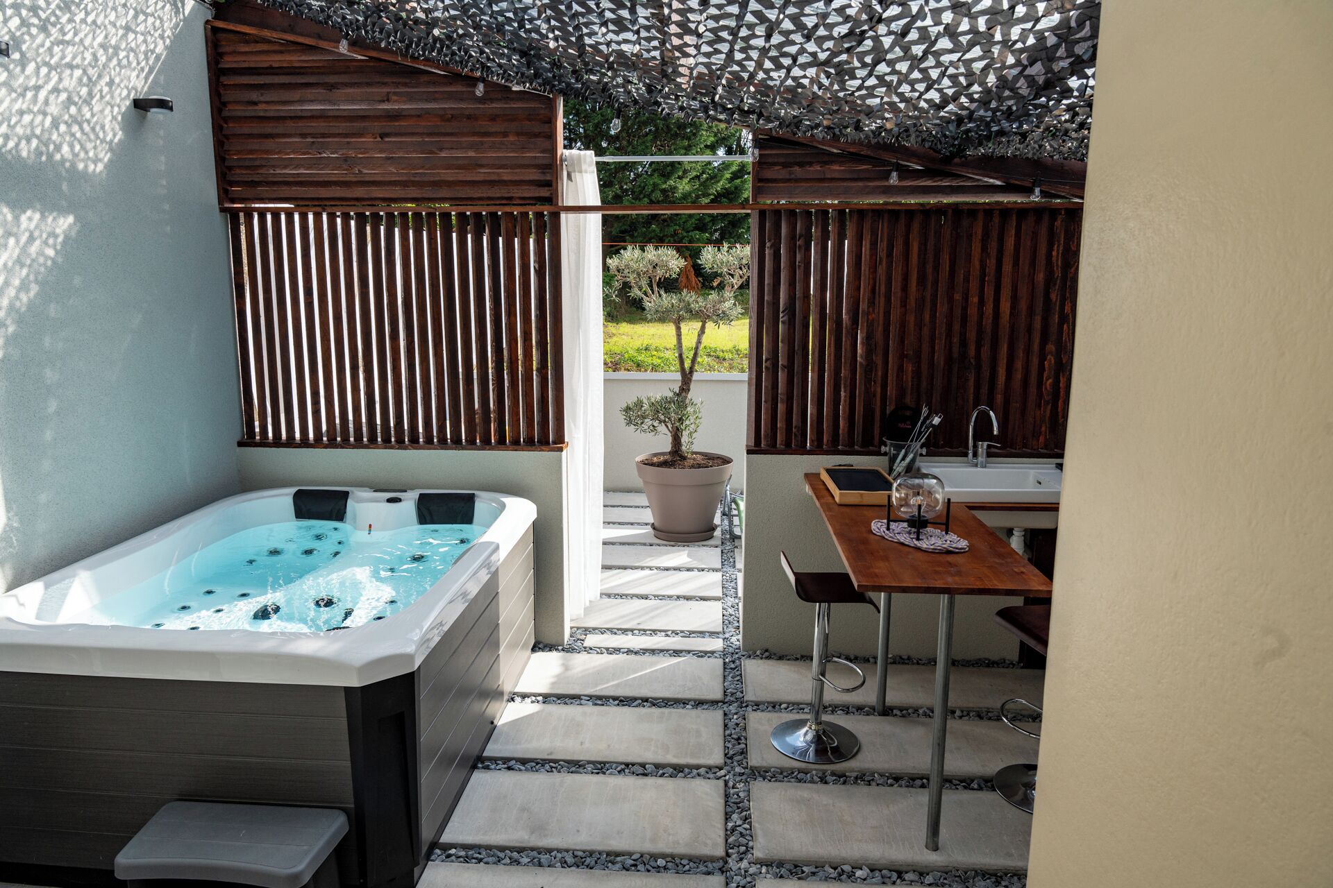 A spa area with a hot tub, a small table with a sink, and a potted plant.