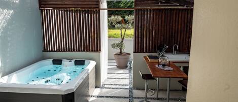 A spa area with a hot tub, a small table with a sink, and a potted plant.