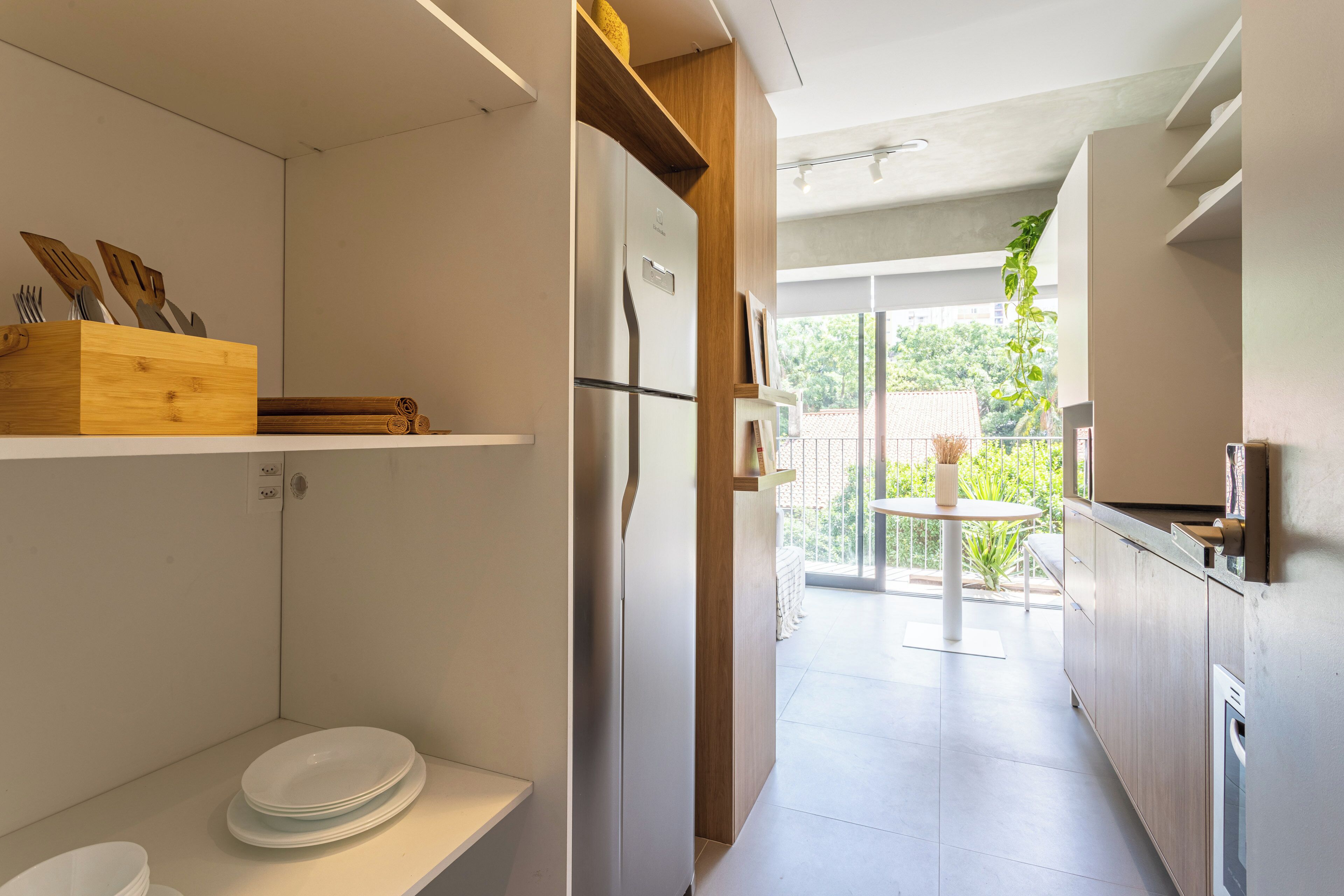 A modern kitchen with white cabinetry, a built-in oven, and a dining area with a table and chairs.
