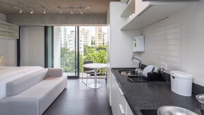 A modern apartment with a kitchenette, a dining area, and a balcony with a view of the city. - Charlie Onze22 Vila Madalena (São Paulo)