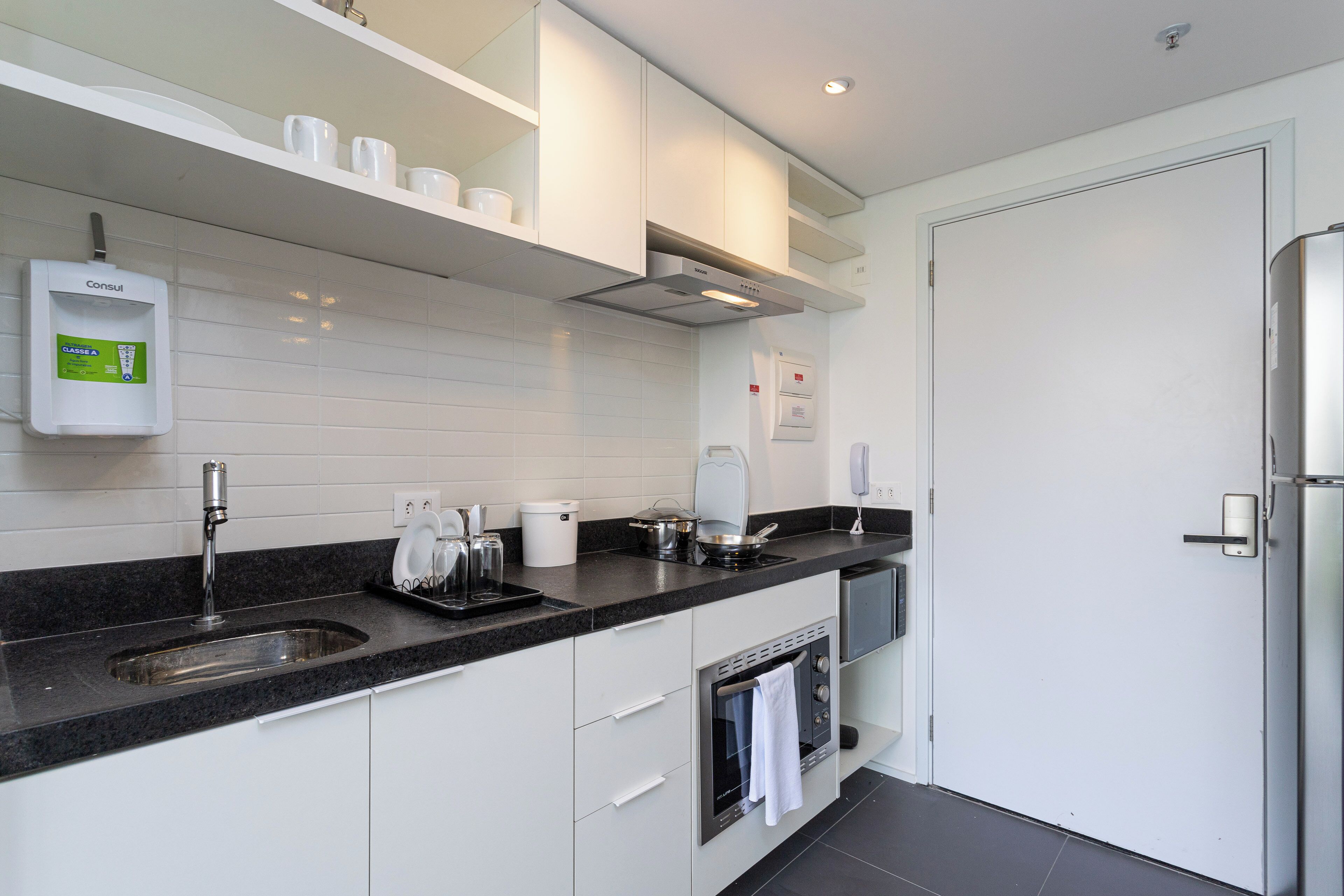 A modern kitchen with white cabinets, a stainless steel sink, and a built-in oven.
