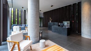 A modern lobby with a reception desk, seating area, and large pillars. - Charlie Onze22 Vila Madalena (São Paulo)