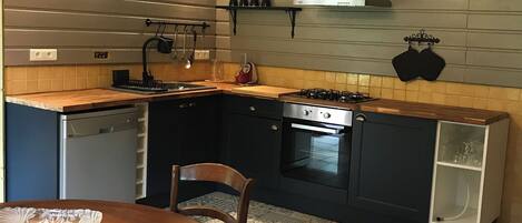 Une cuisine moderne avec un coin repas, comprenant une cuisinière, un four et des placards intégrés.