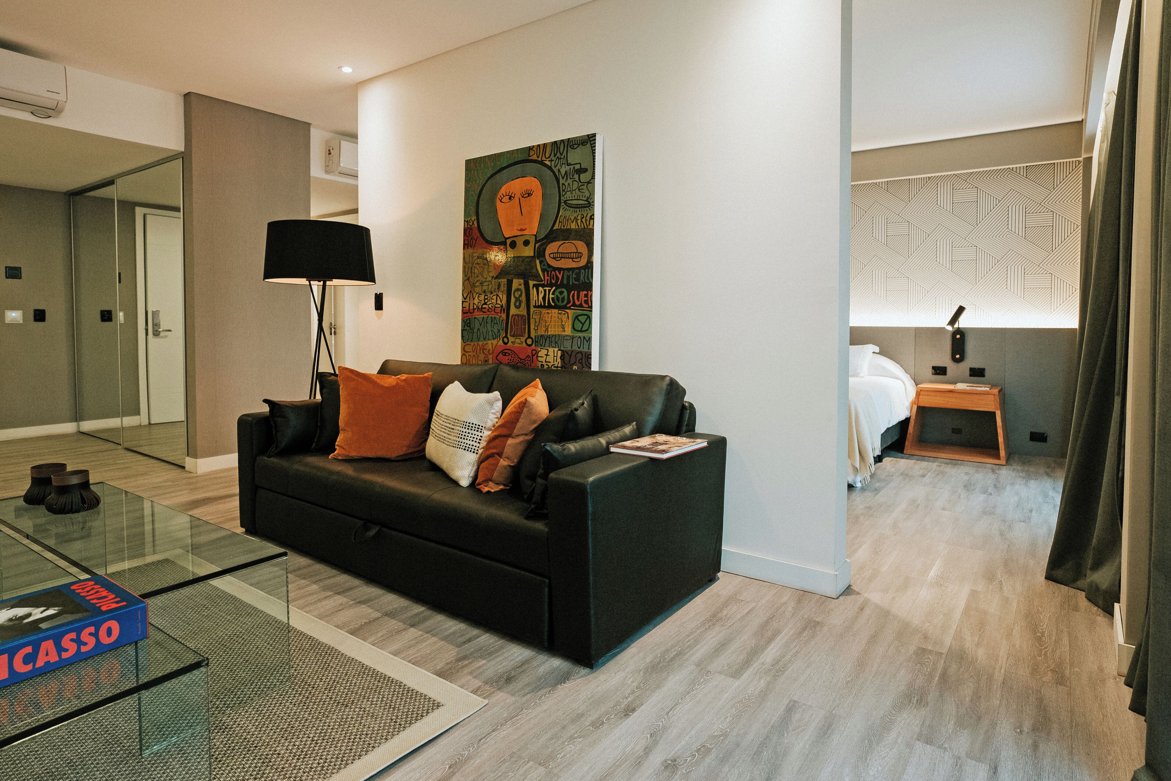 En moderne stue med en sort sofa, et glasbord og et billede på væggen.