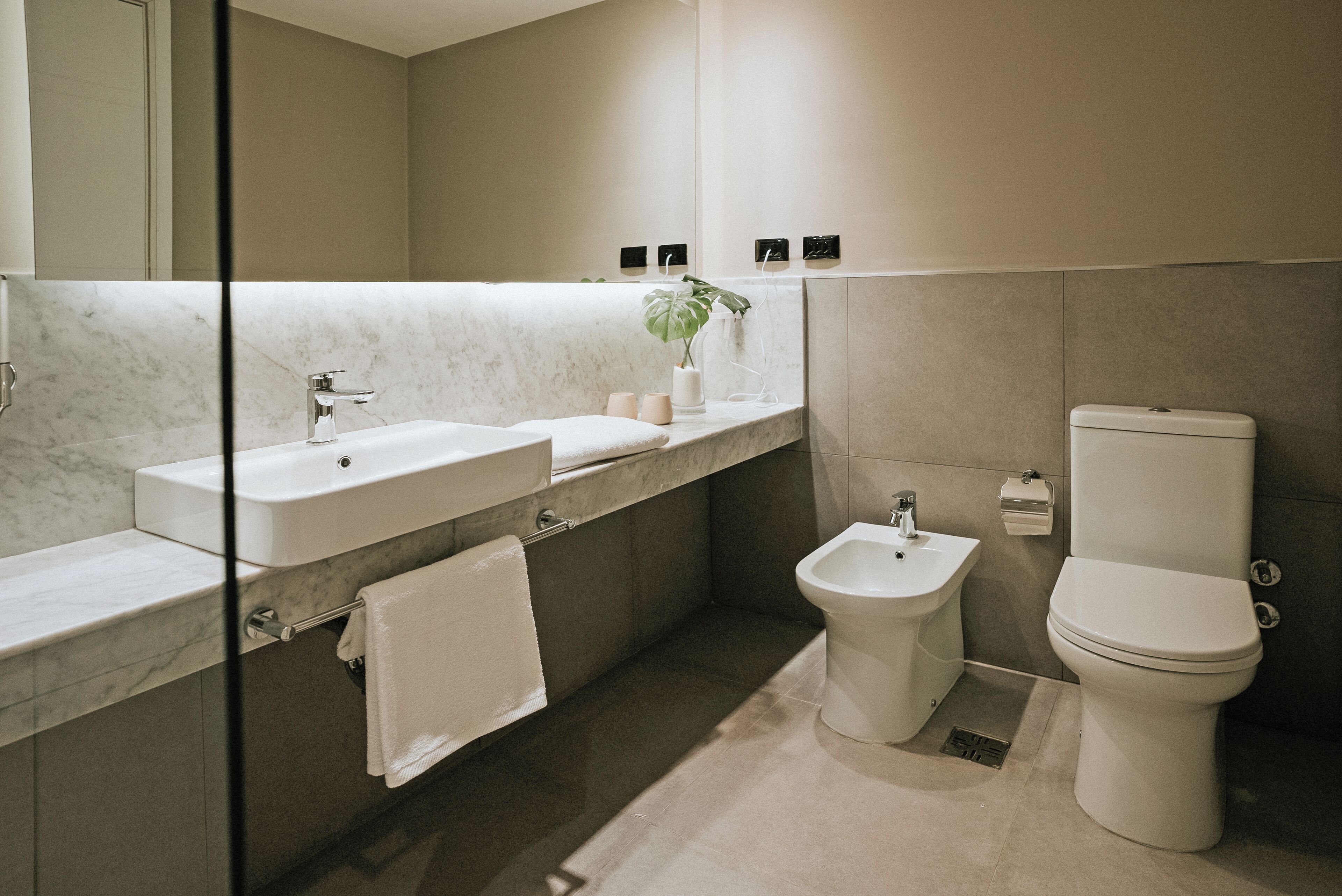 A modern bathroom with a marble vanity, a bidet, and a toilet.