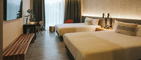 A hotel room with two beds, a desk, a chair, and a bench.