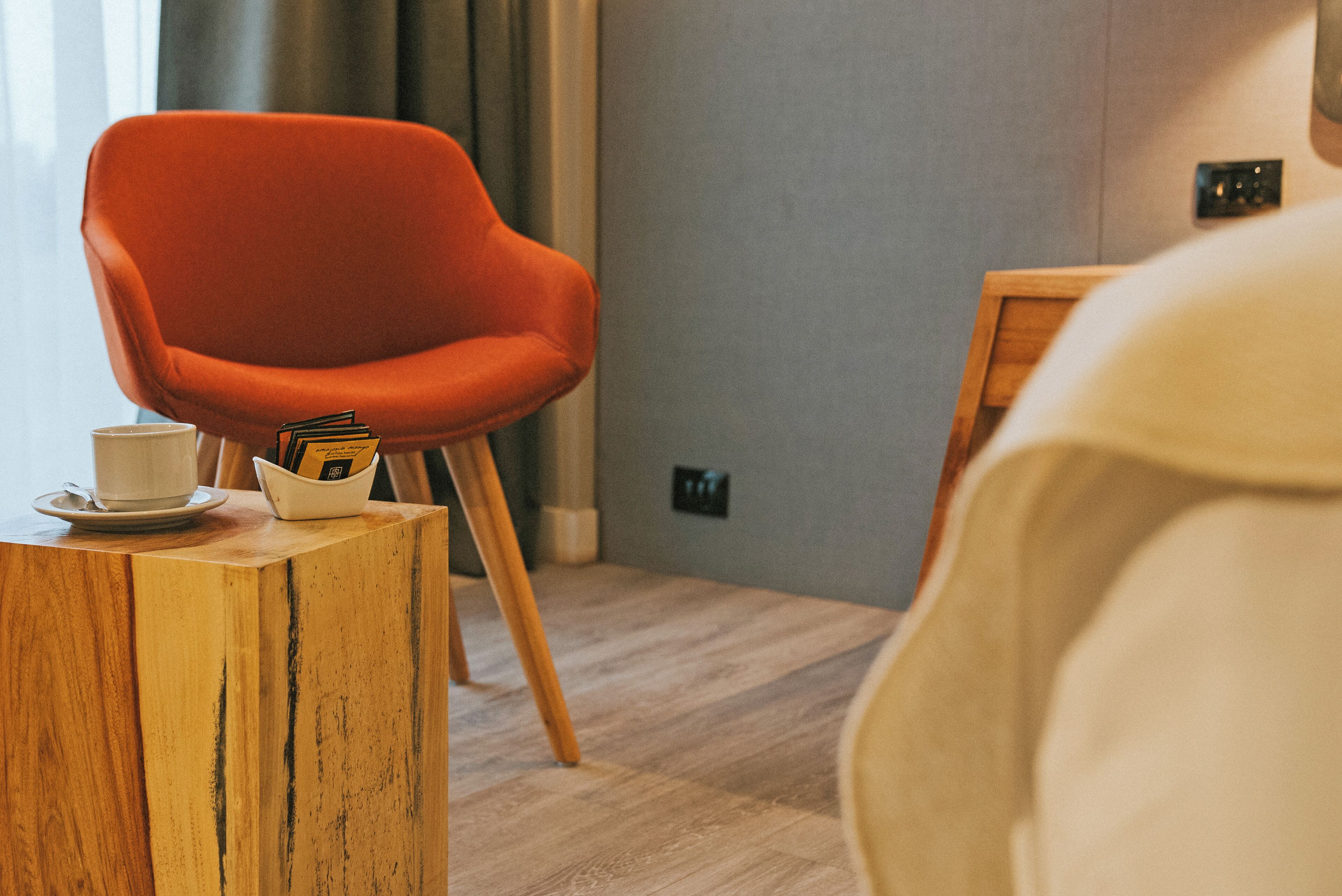 A modern room with a wooden coffee table, a red chair, and a white bed.