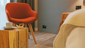 A modern room with a wooden coffee table, a red chair, and a white bed.