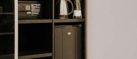 A kitchen area with a microwave, kettle, and a cabinet.