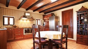 Una cocina con armarios de madera, salpicadero de azulejos, una isla central y una mesa de comedor con sillas.