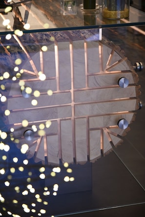 A wooden table with a geometric pattern and metal knobs, placed on a glass surface. - Outside Hotel (Foggia)