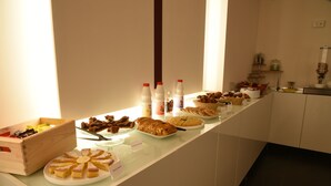 Ein Buffet mit verschiedenen Speisen, darunter Kuchen, Gebäck und Getränke.