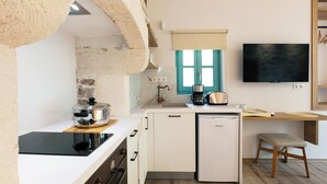 Eine kompakte Küche mit Backofen, Kaffeemaschine und kleinem Kühlschrank.