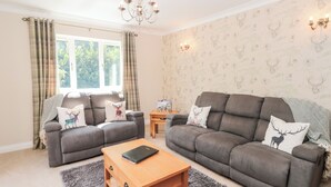A living room with two grey sofas, a wooden coffee table, and a chandelier. - Church View (Hull)