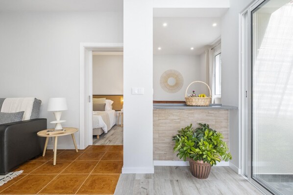 Un salon moderne avec un canapé, une petite table sur laquelle se trouve une lampe, et une plante en pot.
