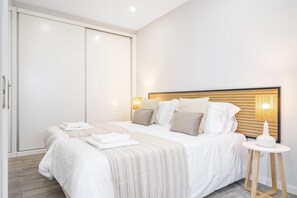 Une chambre à coucher moderne avec un grand lit, des lampes de chevet et une petite table.