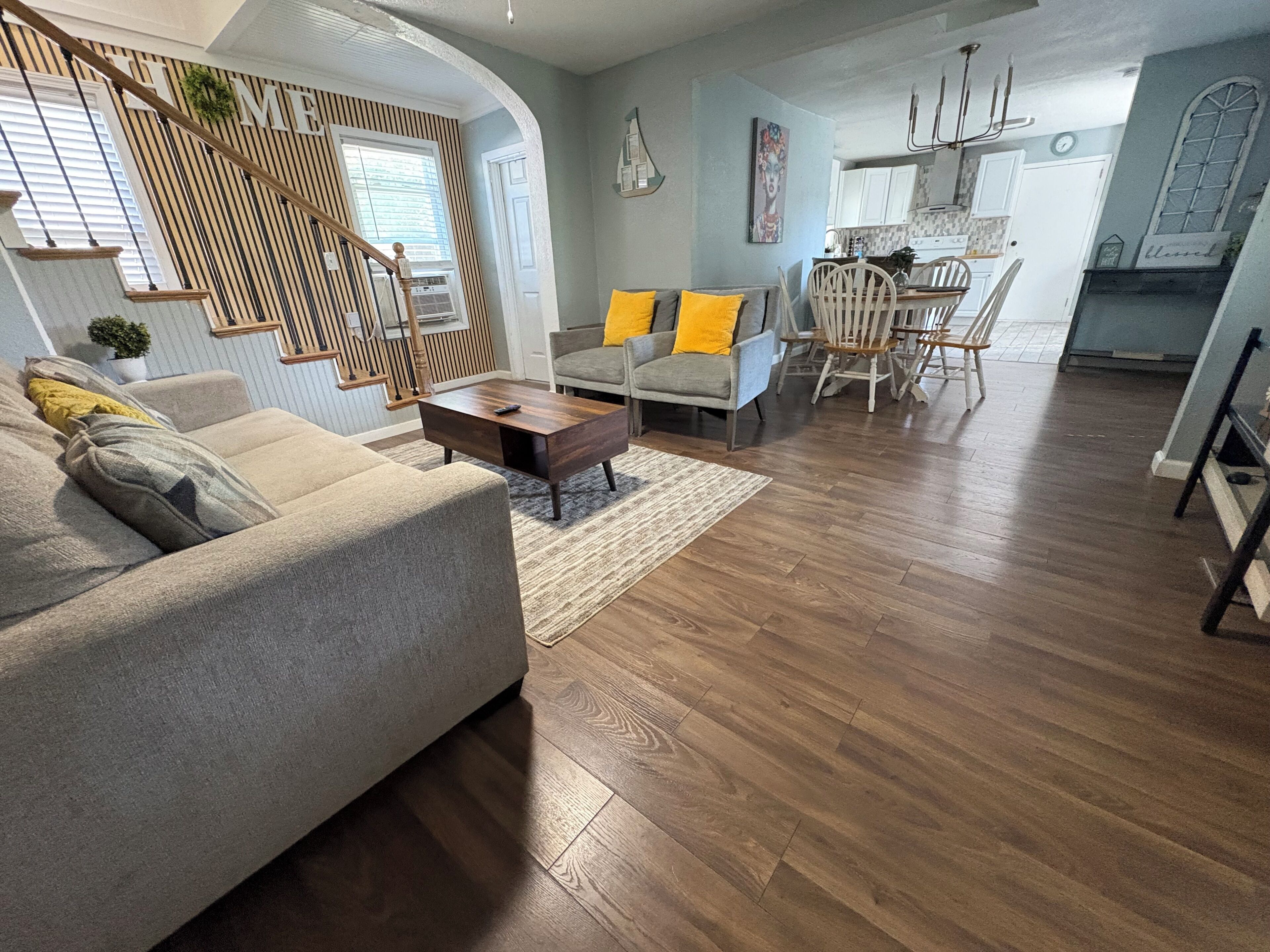 A modern living room with a sofa, coffee table, and chairs. There is a staircase leading to another level.