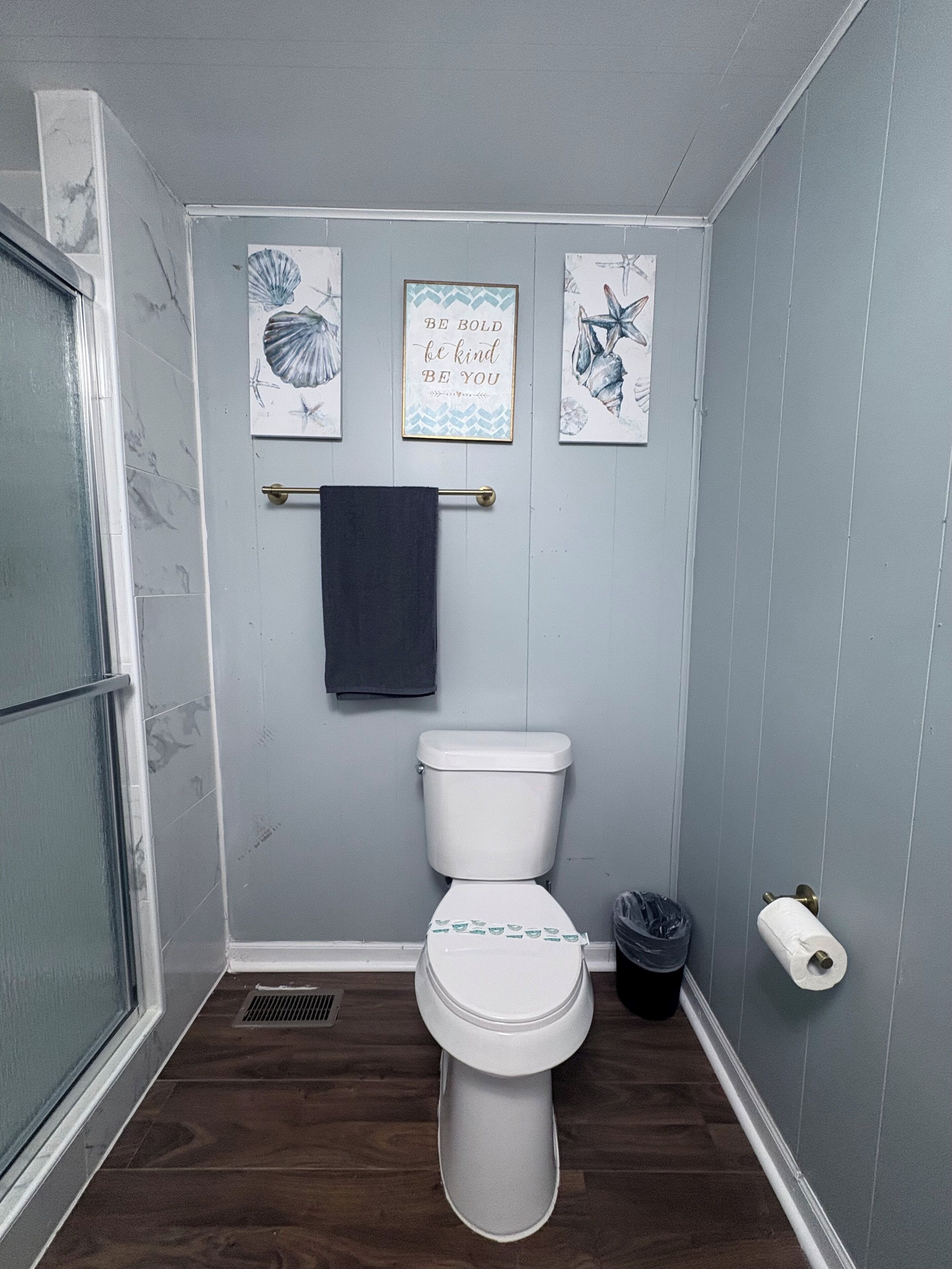 Une salle de bain équipée de toilettes, d’un porte-serviettes et de trois tableaux encadrés accrochés au mur.