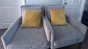 Two grey armchairs with yellow cushions, a wooden wall decoration with two arched windows, and a white door. - Cheerful Bronson Cutie
 (Bronson)