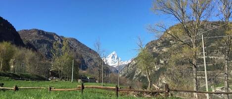 A mountainous landscape with a clear sky, a wooden fence, and a distant snow-capped peak.