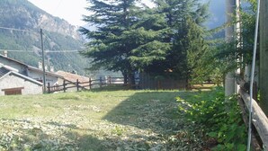 A rural property with a stone building, a wooden fence, and a large coniferous tree.