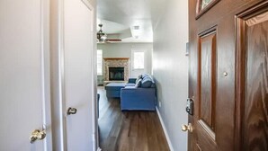 A hallway leading to a living room with a blue sofa and a fireplace. - 4 bed/ 2 bath gem
 (Killeen)
