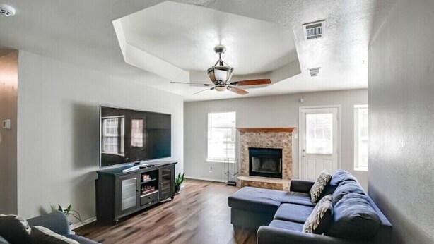 A living room with a fireplace, a ceiling fan, and a television. - 4 bed/ 2 bath gem
 (Killeen)