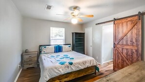 A bedroom with a bed, a nightstand, a ceiling fan, a wardrobe, and a sliding barn-style door. - 4 bed/ 2 bath gem
 (Killeen)
