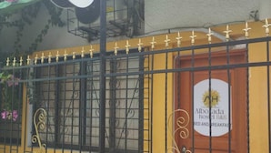 A hostel with a yellow exterior, a metal gate, and a sign indicating it offers bed and breakfast services. - alborada hostel B&B  (Santa Marta)