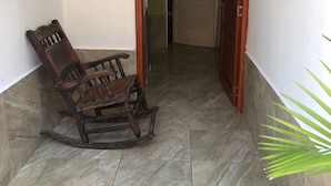 A narrow hallway with a wooden rocking chair and a door leading to another room. - alborada hostel B&B  (Santa Marta)