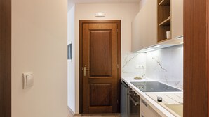 Eine schmale Küche mit Holztür, eingebautem Ofen und Marmorfliesenspiegel.