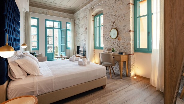Ein Schlafzimmer mit einem großen Bett, einem Schreibtisch, einem Stuhl und einem Fernseher.