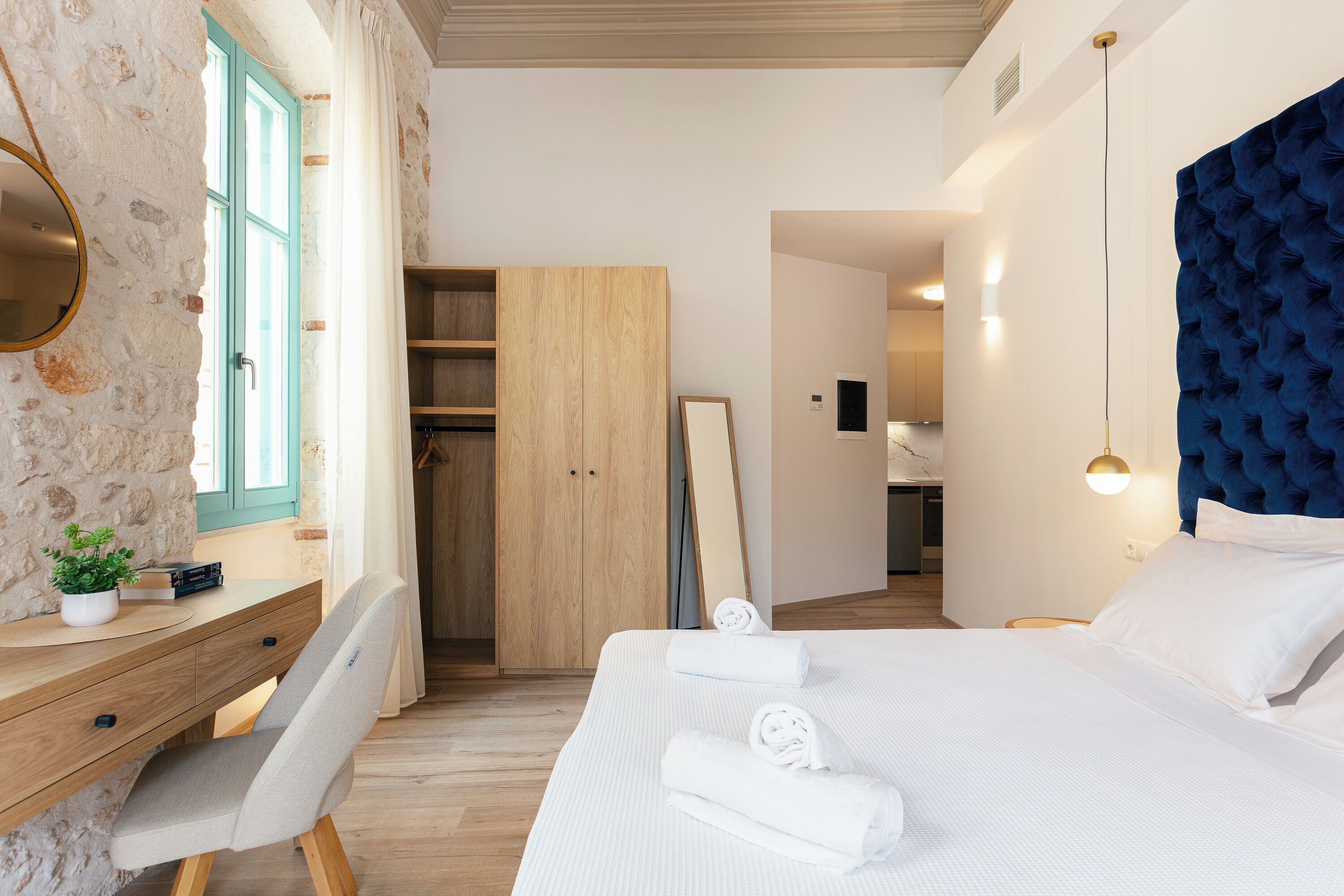A bedroom with a bed, a desk, a chair, a wardrobe, and a mirror.